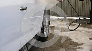 Close-up of a woman washing a car at a self-service car wash.