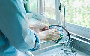 Close-up of a woman washing dishes with dirty food scraps Cleaner in the sink the kitchen counter at home