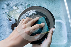 Close-up of a woman washing dishes with dirty food scraps Cleaner in the sink the kitchen counter at home