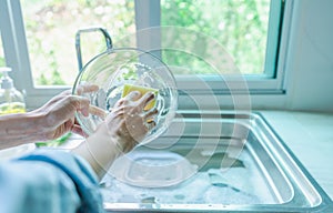 Close-up of a woman washing dishes with dirty food scraps Cleaner in the sink the kitchen counter at home