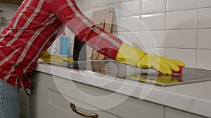 Close-up of woman washing electric cooktop from grease using spray detergent