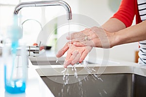 Close Up Of Woman Washing Hands In Kitchen Sink