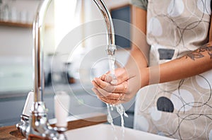 Close up of woman washing her hands in sink with tap water in the kitchen at home. Always wash your hands before cooking