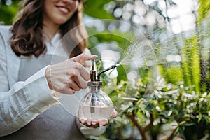 Close up of woman watering plants in a greenhouse.