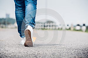 Close up woman wear jean and white sneaker walking forward on hi