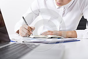 Close up of a woman in a white blouse who is writing