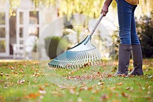 Close Up Of Woman Working In Garden At Home Raking And Tidying Leaves