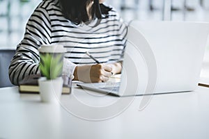 Close up of woman working or writing something on the book in the workplace