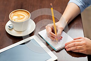 Close up of woman writing to notebook with pencil