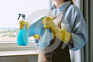 Close-up of woman& x27;s hands in gloves with rag detergent spray for cleaning windows photo