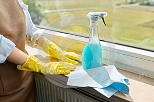 Close-up of woman's hands in gloves with rag detergent spray for cleaning windows photo