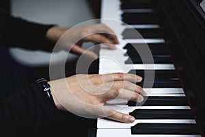 Close up of woman& x27;s hands playing piano by reading sheet music. Dark mood.