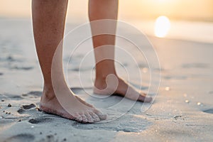 Close-up of womans feet in sand, at sea.