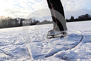 Close up on womans feet wearing ice skating boots and standing on ice