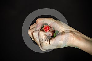 Close up womans hand clenching flowers in a fist.