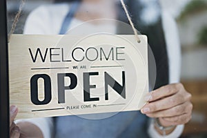 Close up of womanÂ€Â™ hands holding sign now we are open support local business