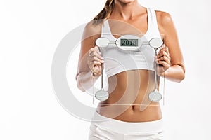 Close up of womanâ€™s abdomen, holding a weight scale with a year 2018 written on it