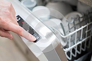 Close Up Of Womanâ€™s Hand Pressing Start Button On Dishwasher