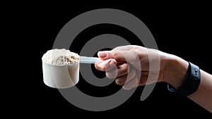 Close up of women hand holding a measuring scoop of whey protein  preparing protein shake