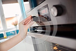 Close up of women hand setting cooking mode on oven