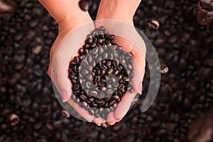 Close up of women`s hands with coffee beans on coffee bottom with levitating grains