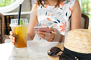 Close up of women`s hands holding drinks while using mobile phone in cafe