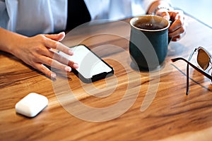 Close up of women's hands holding mobile phone with blank screen in cafe
