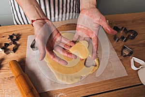 Close up women's hands lay out the formed cookies in the form of a heart on a baking sheet. Cooking desserts at home