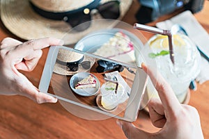 Close up of women`s hands take a photo of cheese cake and drinks