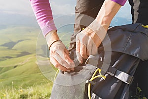 Close-up of women`s hands unfasten the buckle on the camp backpack against the background of the valley in the setting