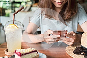 Close up of women`s hands using mobile phone on wooden table in cafe.