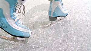 Close-up of women`s legs on skates in winter on an skating rink. Scene. Woman skating close-up