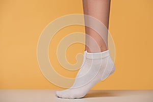 Close-up women`s legs in white socks close-up. Yellow background