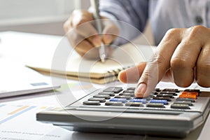 Close-up of women using calculators and note-taking, accounting reports.