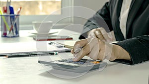 Close-up of women using calculators and note-taking, accounting reports.