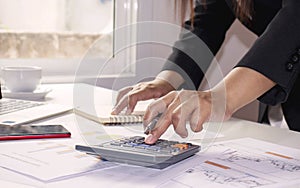 Close-up of women using calculators to create accounting reports by the window in their own homes, cost calculation concepts.