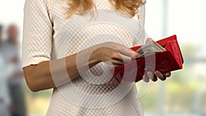 Close up womens hands open a red wallet with money.