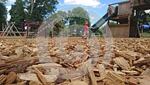 Close up of wood chippings and children playing on a playground