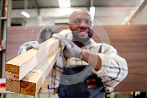 Close-up of wood planks that be carried by middle-aged African carpenter wears apron, worker man makes wooden furniture in