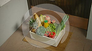 CLOSE UP: Wooden box full of vibrant organic produce sits at someone's doorstep.