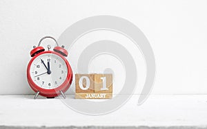 Close up of wooden calendar date 01 January with red alarm clock