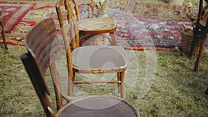 Close-up of wooden chairs and old fashioned carpet, beautiful concept of outdoor wedding ceremony, slow motion shot.