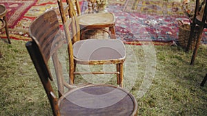 Close-up of wooden chairs and old-fashioned carpet, beautiful decoration on outdoor wedding ceremony. Summer wedding