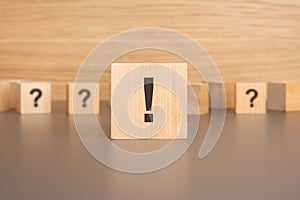 Close-up: a wooden cube with an exclamation mark lies on the table, small wooden cubes with question marks in the