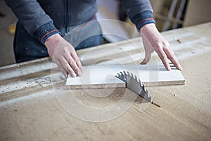 Close-up of a wooden cutting table with an electric circular saw. Professional carpenter cutting a wooden board at a sawmill.