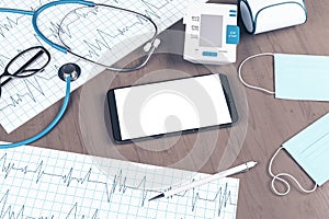 Close up of wooden desk top with blank clean smartphone, stethoscope, cardiogram, pen, other items and mock up place. Doctor`s
