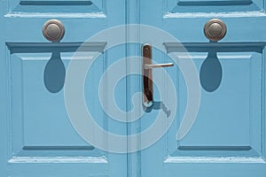 Close-up of wooden door painted in blue with round knobs