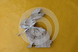 Close up on a wooden easter bunny on a yellow tablecloth with copy space