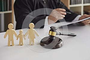 Wooden figurines of family with child and gavel on background of judge conducting divorce process. photo