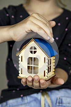 Close-up of a wooden house in hands. The concept of selling real estate, mortgages, rental housing, banking transactions